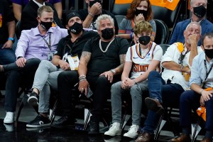 Restaurateur Guy Fieri, middle, watches the Phoenix Suns and the Milwaukee Bucks during the second half of Game 1 of basketball's NBA Finals, Tuesday, July 6, 2021, in Phoenix. The Suns defeated the Bucks 118-105. (AP Photo/Ross D. Franklin)