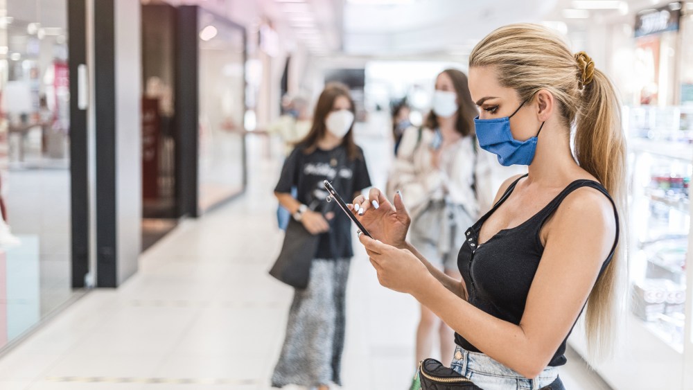 Young woman with face mask in the shopping  during virus pandemic.  New normality. Coronavirus concept.
