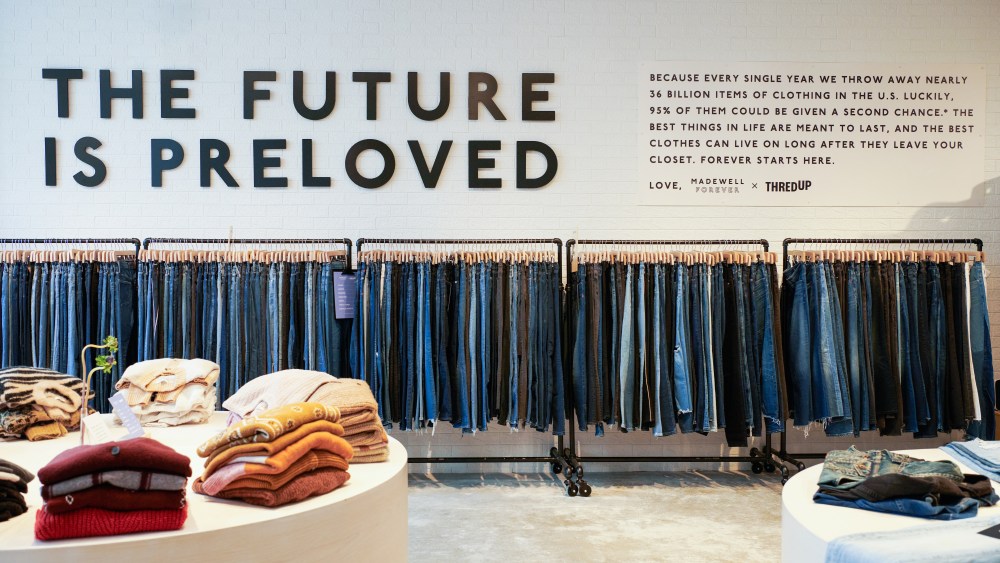 ThredUp store featuring a display of jeans hung on racks under a sign that reads "The Future is Preloved"