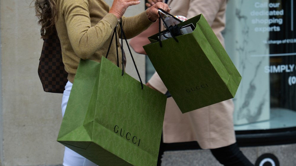 A woman carries luxury shopping bags.