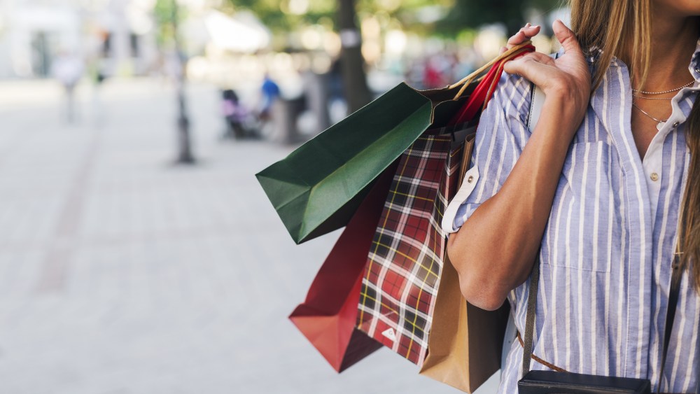 Pretty tourist woman holding shopping bags in city