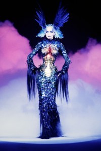 Model Adriana Karembeu presents the La Chimere ensemble, a long sleeved sheath dress with articulated corset of 'scales', made of feathers and horsehair embellished with Swarovski crystals; made in collaboration with Jean-Jacques Urcun and Mr Pearl. Known as La Chimre collection, Mugler's couture and ready to wear lines were presented together in a single runway show.

Thierry Mugler Fall 1997 Couture And Ready To Wear Runway Show