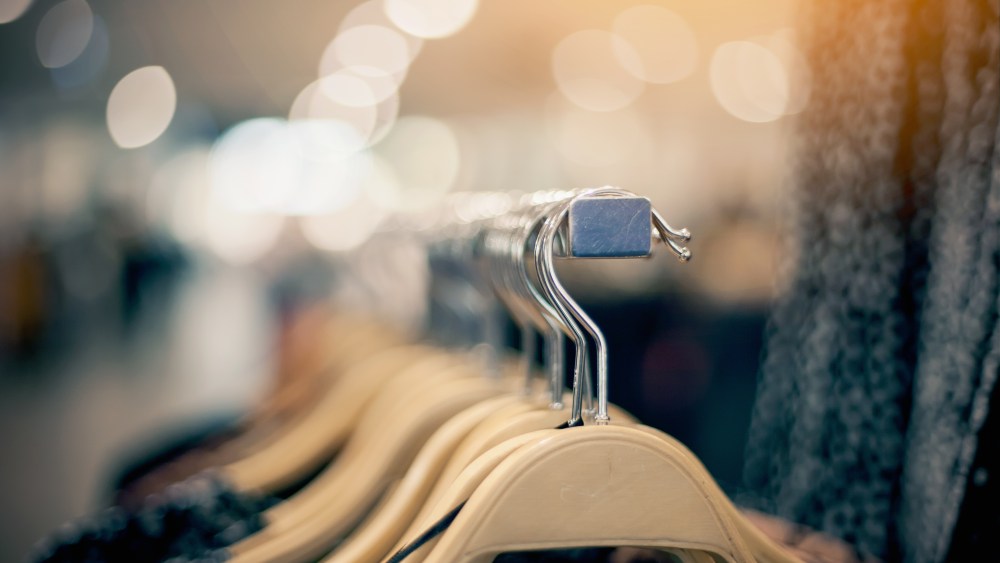 Shopping in store. Clothes on hangers in shop for sale. Blur background. Fashionable clothes in a boutique. Various clothing on market.