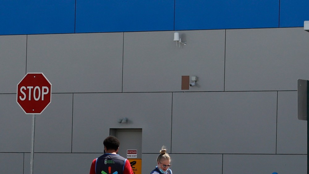 Workers sanitize items outside a Walmart that has been closed following the deaths of three people connected to the store after being infected by the new coronavirus and at least six other employees testing positive for COVID-19 Friday, April 24, 2020, in Aurora, Colo. (AP Photo/David Zalubowski)