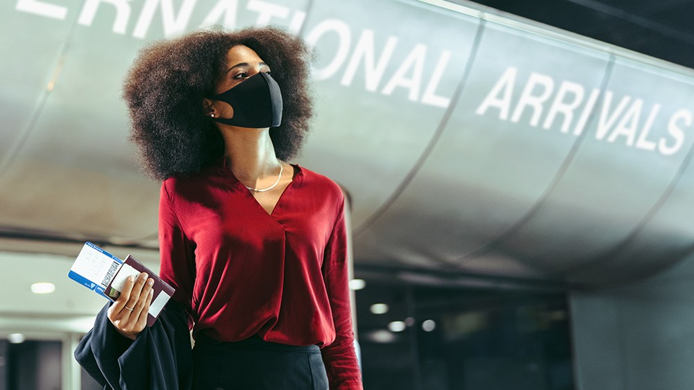 Woman at airport arrivals terminal wearing mask