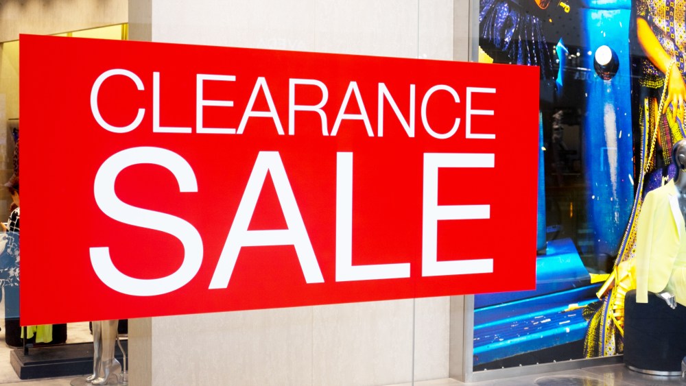 Clearance sale cut out label display on glass window along side with plastic model doll in clothes store in fashion mall