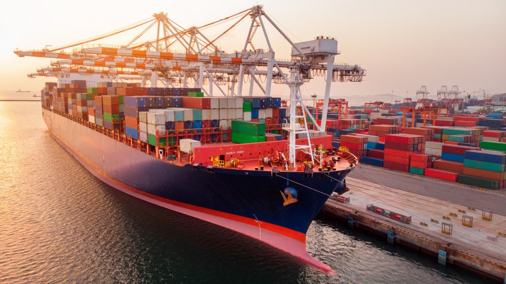 crane loanding cargo container to container ship in the international terminal yard port  concept freight shipping by ship at sunrise .
