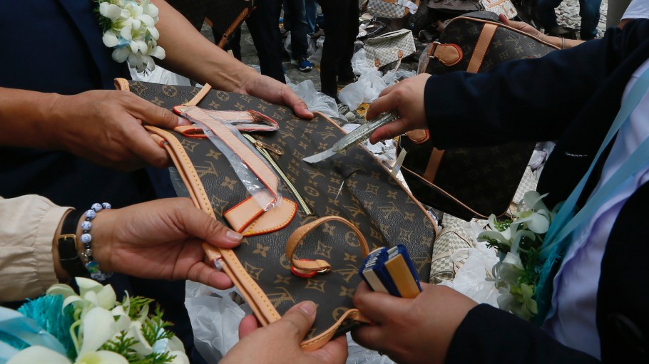 A counterfeit Louis Vuitton bag being cut open by police.