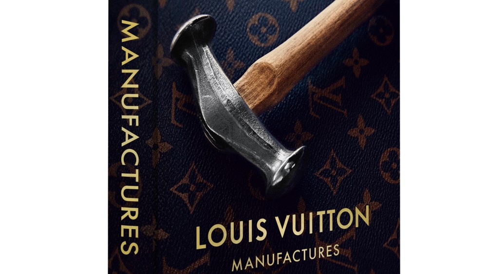 The cover of "Louis Vuitton Manufactures" published by Assouline featuring the company's monogram logo all over and a large hammer on top.