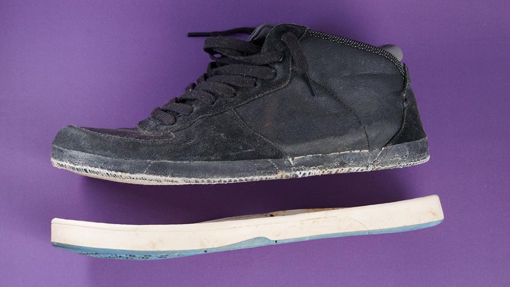 sneaker anatomy, inside of a sneaker, Old broken sneakers shoes with cracked sole on purple background.
