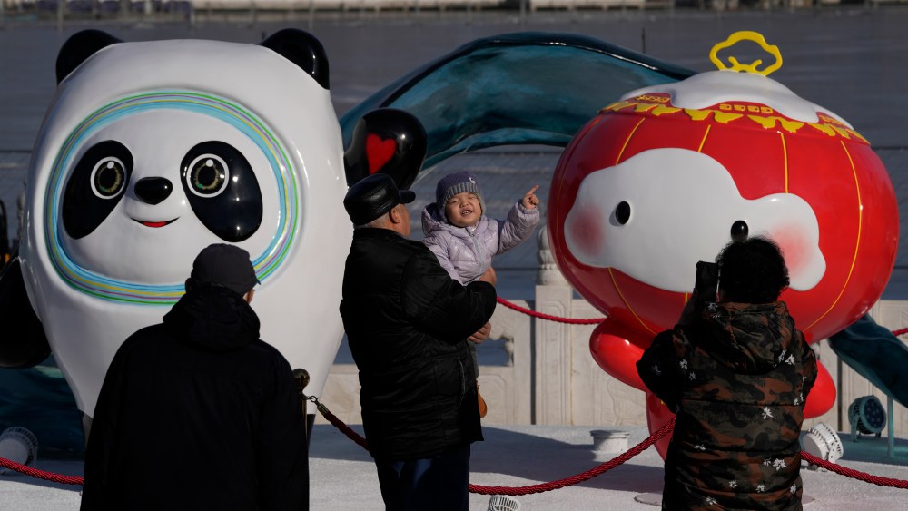 A child reacts near the Winter Olympics and Paralympics mascots, Bing Dwen Dwen, and Shuey Rhon Rhon along a lake in Beijing, China, Monday, Feb. 7, 2022. As China gets back to business after a muted Chinese New Year holiday that coincided with the start of the pandemic-restricted Beijing Olympic Winter Games, the feeling inside and out of the bubble in this auspicious Year of the Tiger is that festivities for the most sacred and important holiday for the country were limited and underwhelming. (AP Photo/Ng Han Guan)