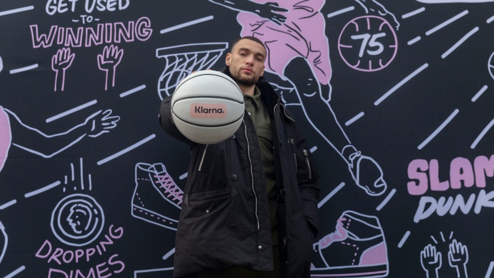 Zach LaVine in front of a mural designed by Sophia Chang at the Klarna All-Star Vault activation during NBA All-Star Weekend in Cleveland.