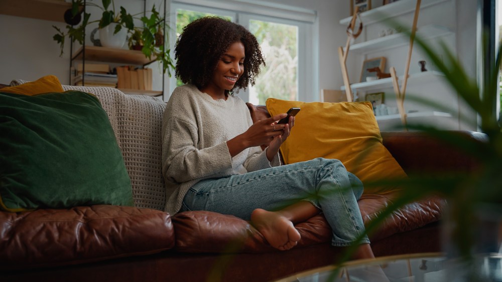 Woman sitting on couch using mobile phone