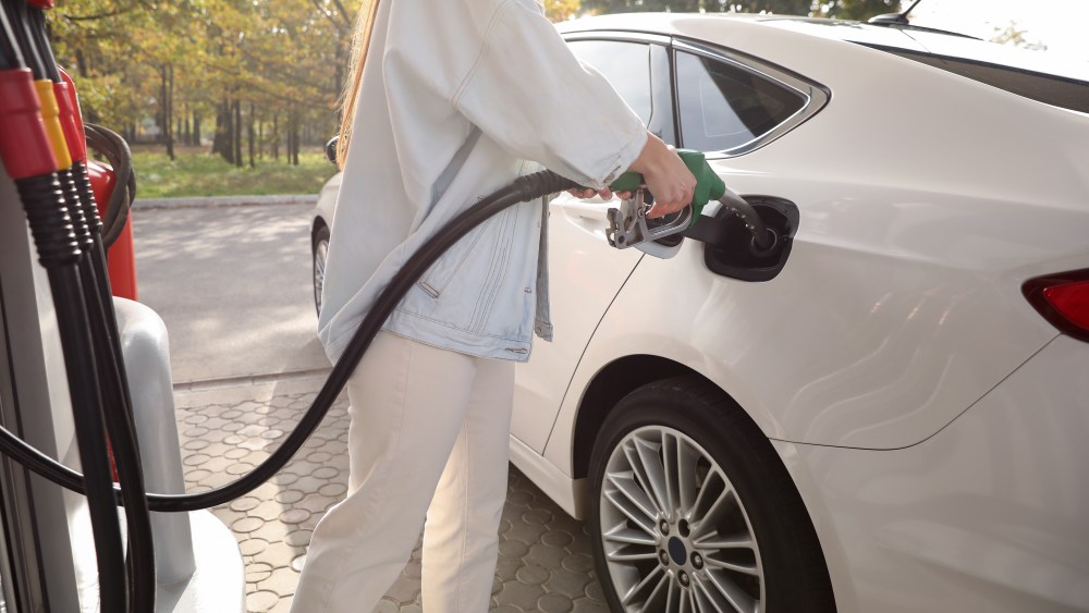 Woman refueling car at self service gas station, closeup