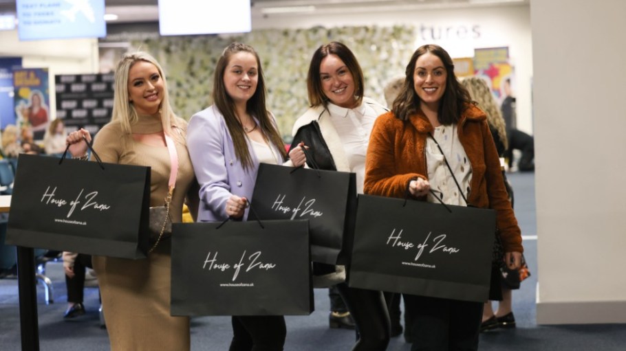Shoppers holding bags showcasing the "House of Zana" logo.