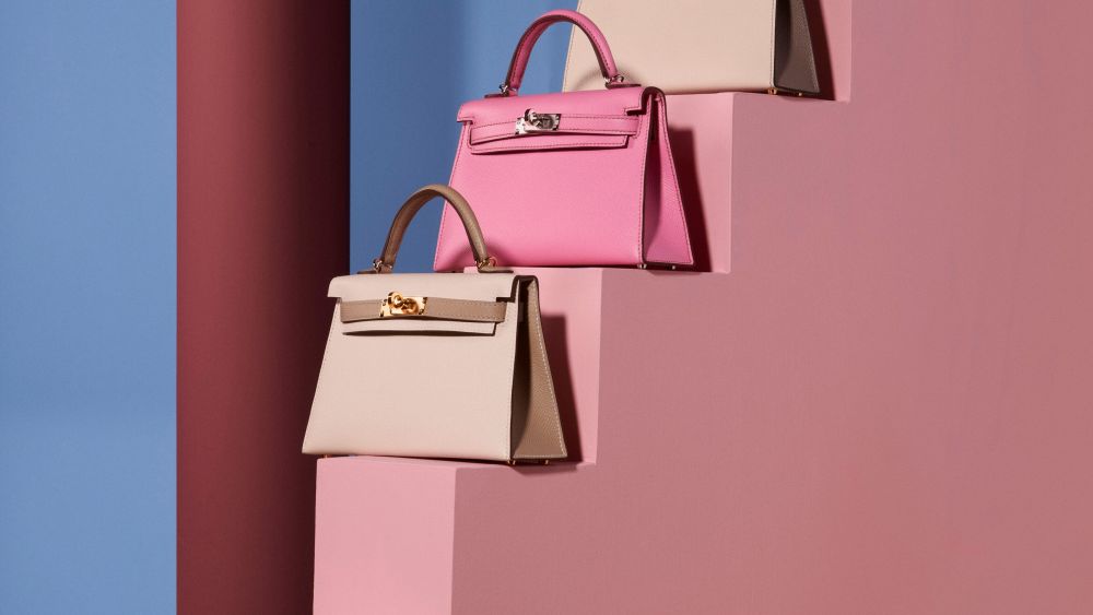 A pink staircase displays a trio of pink-washed Hermès bags.