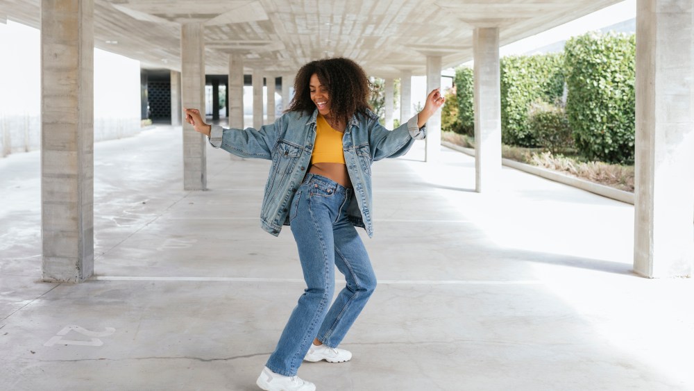 Portrait of smiling African American woman with urban look dancing in an empty parking in Granada, Spain