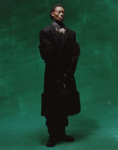 Prada’s virgin wool, nylon and mohair wool overcoat, cotton and nylon knit turtleneck and recycled polyamide Re-Nylon jumpsuit.Ami gloves; Prada boots; Thom Browne briefcase.RJ Graziano Necklace