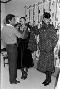 Valentino adjusts a look from his Fall 1977 Couture collection on Sara Kapp and a model at his atelier in Rome, Italy on July 25, 1977.