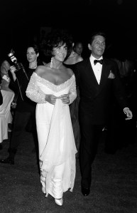Elizabeth Taylor in a white lace trimmed Valentino dress arrives with  Valentino Garavani for the House of Valentino's "30th Years in Fashion" exhibition and party in Rome, Italy on June 7, 1991.