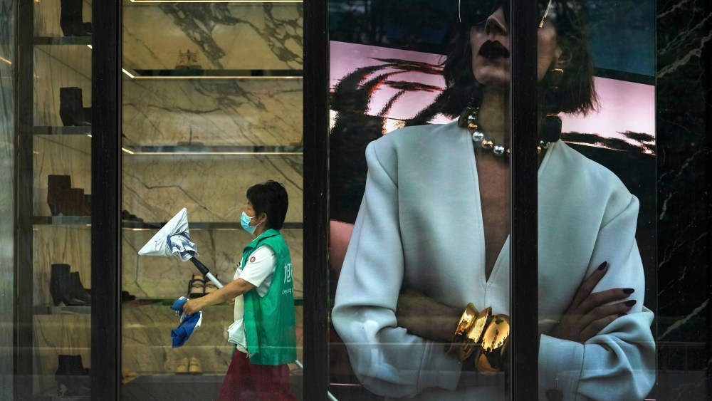 A worker wearing a face mask prepares to clean a fashion boutique inside a reopened shopping mall after bering closed due to COVID-19 restriction in Beijing.