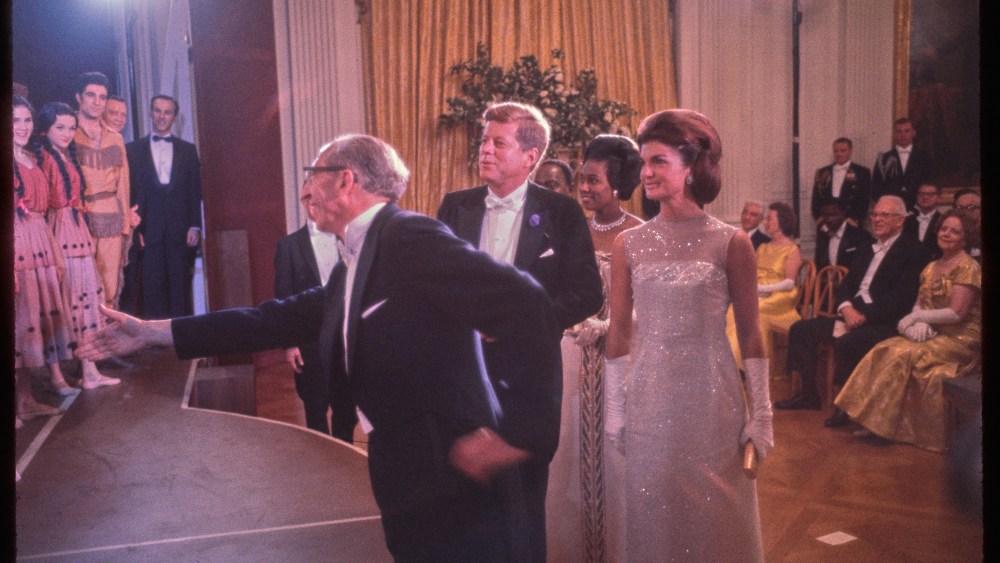 In this photograph, President John F. Kennedy and First Lady Jacqueline Kennedy greet members of the American Ballet Theatre at the conclusion of their performance of "Billy the Kid" in the East Room on May 22, 1962. Joining the Kennedys were President Félix Houphouët-Boigny of the Ivory Coast and his wife, First Lady Marie-Thérèse Houphouët-Boigny. At the forefront of the group is Aaron Copland, composer of the ballet. The ballet was part of the entertainment for the State Dinner held in honor of the President Houphouët-Boigny.