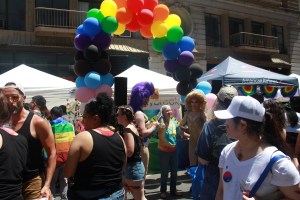 Rainbow balloon banner arches above a few drag queens at NYC Pride March.