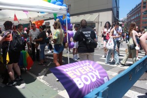 "Freedom for every body" sign stuck amid a fence line at NYC Pride.