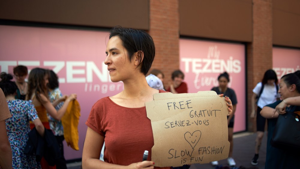 A young woman holds a cardboard reading 'Free , slow fashion is fun'. Members of XR Toulouse (Extinction Rebellion) organized a protest in front of a pop-up SHEIN shop. The chinese brand SHEIN opened a pop-up store in Toulouse only for 4 days. XR wanted to raise awareness about water consumption and waste, over consumption of ressources, workers' conditions and abuse of human rights in China. They are against fast fashion as it's a waste of natural ressources. Toulouse. France. May 28th 2022. (Photo by Alain Pitton/NurPhoto via AP)