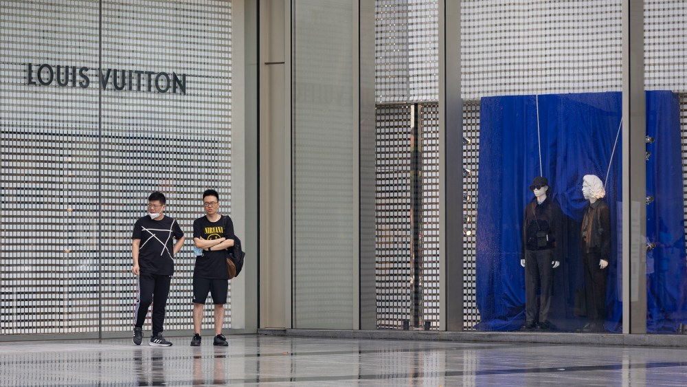 People stand in front of a Louis Vuitton store at Xujiahui in Shanghai, China.