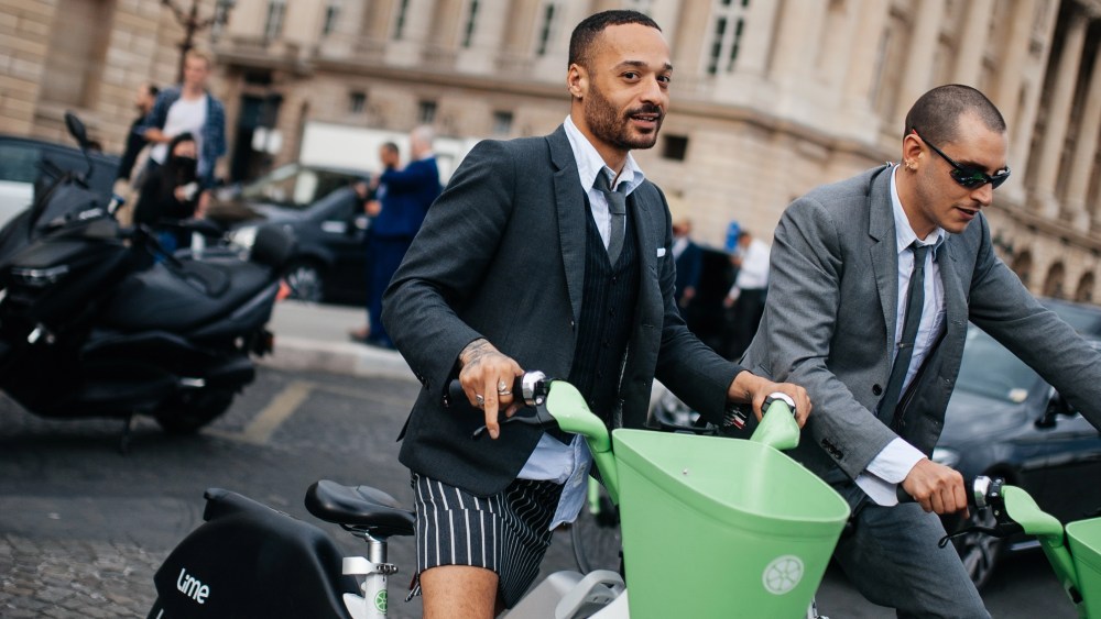 Two men wearing Thom Browne riding Lime e-bikes during Pairs Men's Fashion Week