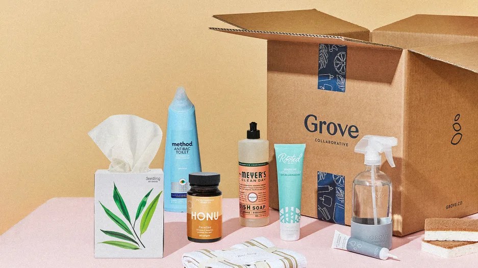 Grove Collaborative's suite of eco-friendly cleaning supplies laid out on a pink table with a tissue box, soap and more on display.