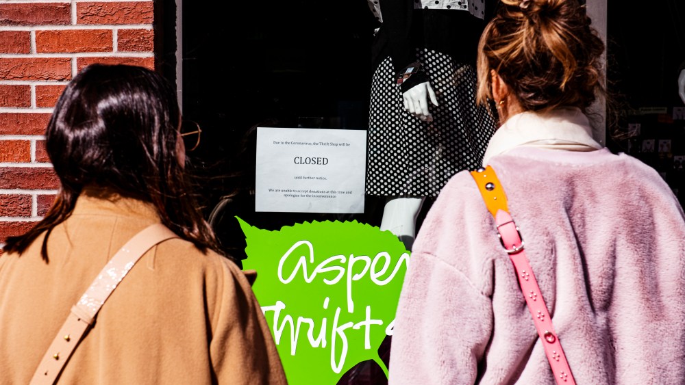 Two women look at the Aspen Thrift Shop's notice of closure due to the coronavirus, Thursday, March 12, 2020, in Aspen, Colo. (Kelsey Brunner/The Aspen Times via AP)