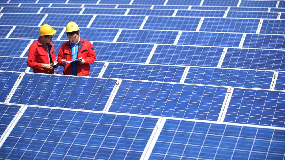 --FILE--Chinese workers check solar panels on the rooftop of a factory building at a textile plant of Jifa Group in Jimo city, east China's Shandong province, 12 May 2014.China will push this year to install almost 2 1/2 times as much solar capacity as the U.S. added in 2014 in a race to clear its increasingly polluted air. The world's biggest emitter of carbon aims to install as much as 17.8 gigawatts of solar projects in 2015, according to a National Energy Administration planning document. The NEA previously estimated 15 gigawatts would be added this year, according to a person familiar with the matter, who asked not to be identified as they weren't authorized to discuss the plan publicly. The more ambitious goal may attract as much as 21 billion yuan (US$3.4 billion) of additional investment to solar projects compared with the earlier plan.