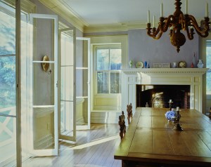 The dining room of the Long Island home of photographer Eric Boman and artist Peter Schlesinger with a bronze Swedish chandelier, a limed oak table, walnut chairs, and a collection of opaline vases and a Wedgewood plate lining the fireplace mantel