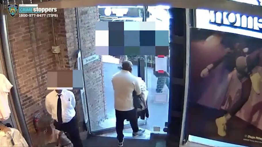 One of seven people who robbed a New York City Lululemon store is seen on video footage carrying a pile of apparel out of the building, while a security guard looks on.