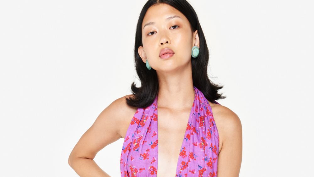 A model with dark hair flipped out sporting statement earrings and a 'Fleance' dress from Couper.