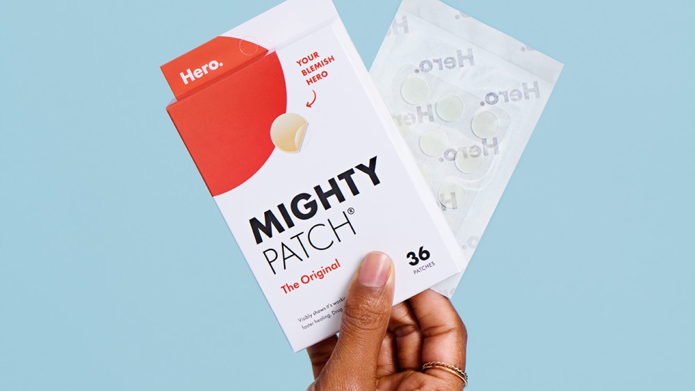 A model's hand against a sky blue backdrop holding up the Hero Cosmetics Mighty Patch Original box.