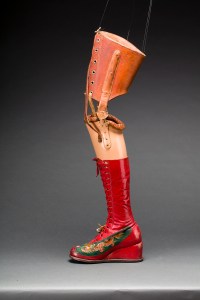 Prosthetic leg with leather boot and appliqued silk with embroidered Chinese motifs.