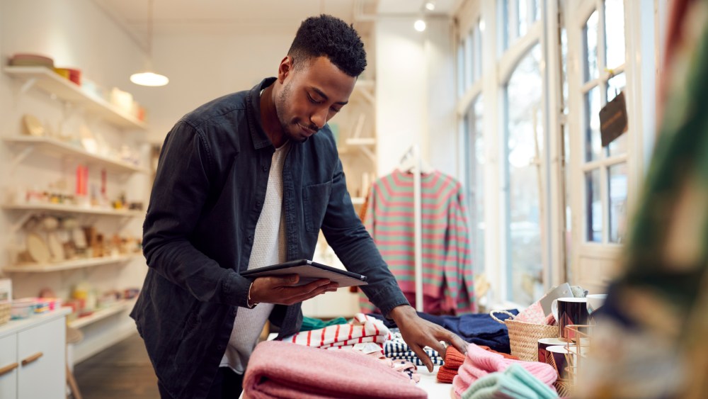 Male Small Business Owner Checks Stock In Shop Using Digital Tablet
