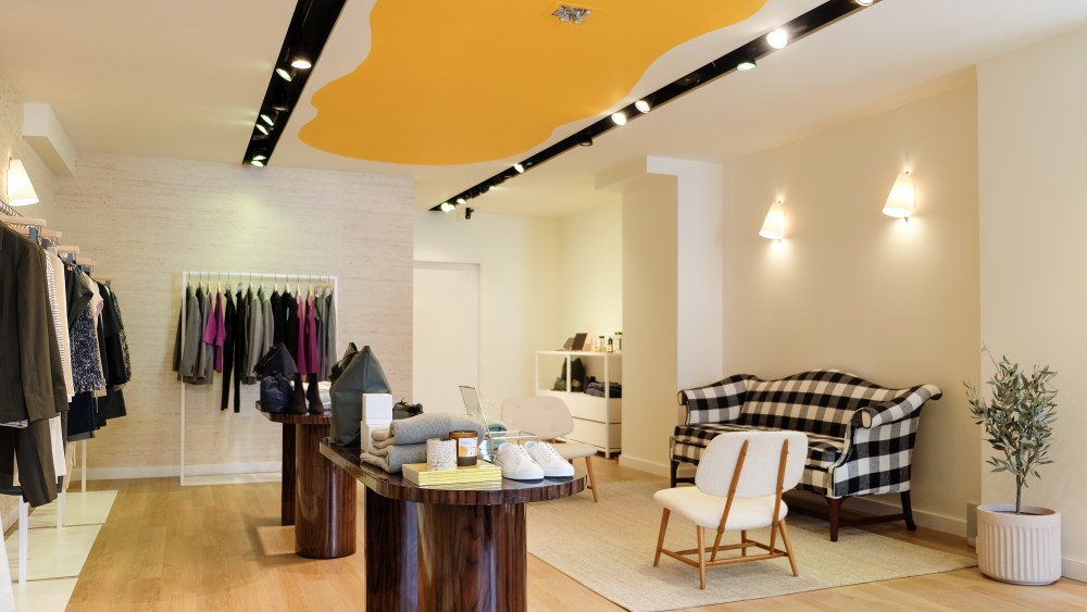 The interior of the store on upper Madison Avenue in New York with yellow paint on the ceiling, a black-and-white checkered couch and spare racks with some clothing giving a minimalist feel to the space.