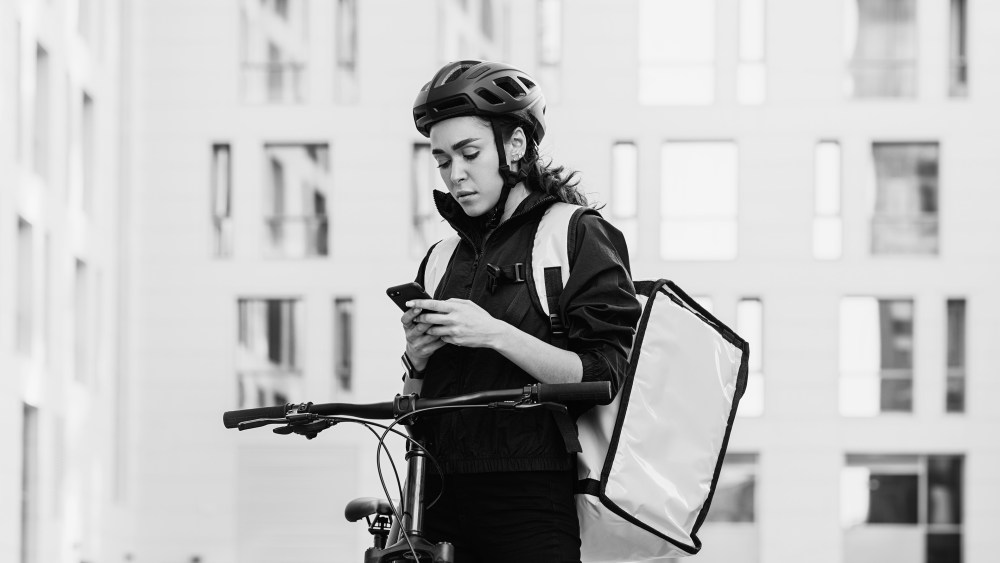 Woman courier with backpack checking information for delivery in the city