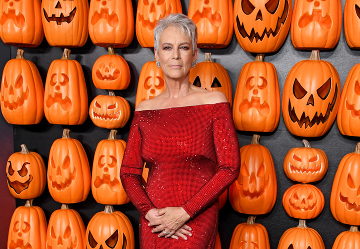 Jaime Lee Curtis poses in red Minali  ralph lauren dress on red carpet at Halloween Ends premiere in Los Angeles.