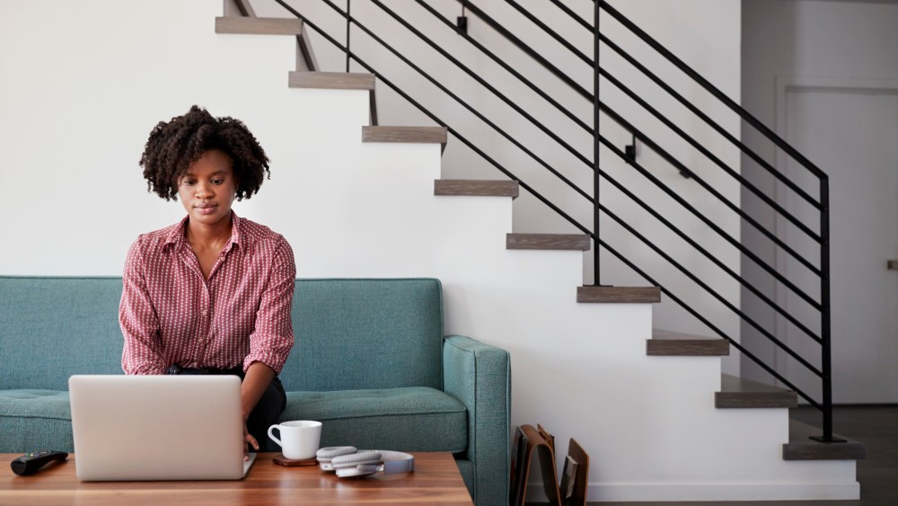 Woman Sitting On Sofa At Home Using Laptop Computer