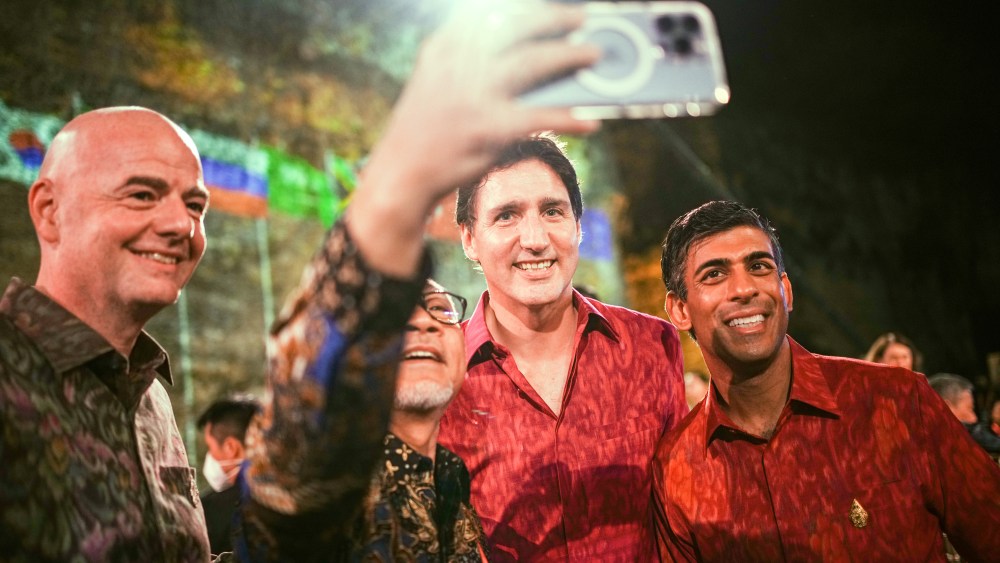 15 November 2022, Indonesia, Nusa Dua: Wearing traditional shirts, Giovanni Infantino (l-r), Fifa president, Justin Trudeau, prime minister of Canada, and Rishi Sunak, prime minister of Great Britain, attend dinner on the sidelines of the G20 summit. In the process, another participant takes a selfie. The group of the G20, the strongest industrialized nations and emerging economies, is meeting for two days on the Indonesian island of Bali. Photo: Kay Nietfeld/dpa (Photo by Kay Nietfeld/picture alliance via Getty Images)