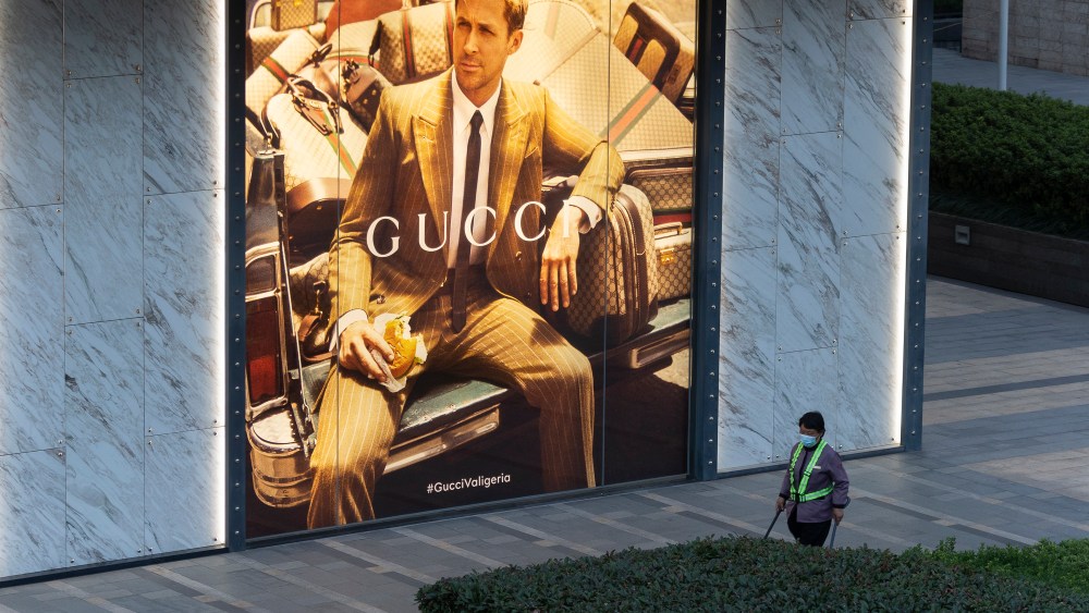 A cleaner with protective mask walks by a luxury shopping mall in Shanghai.
