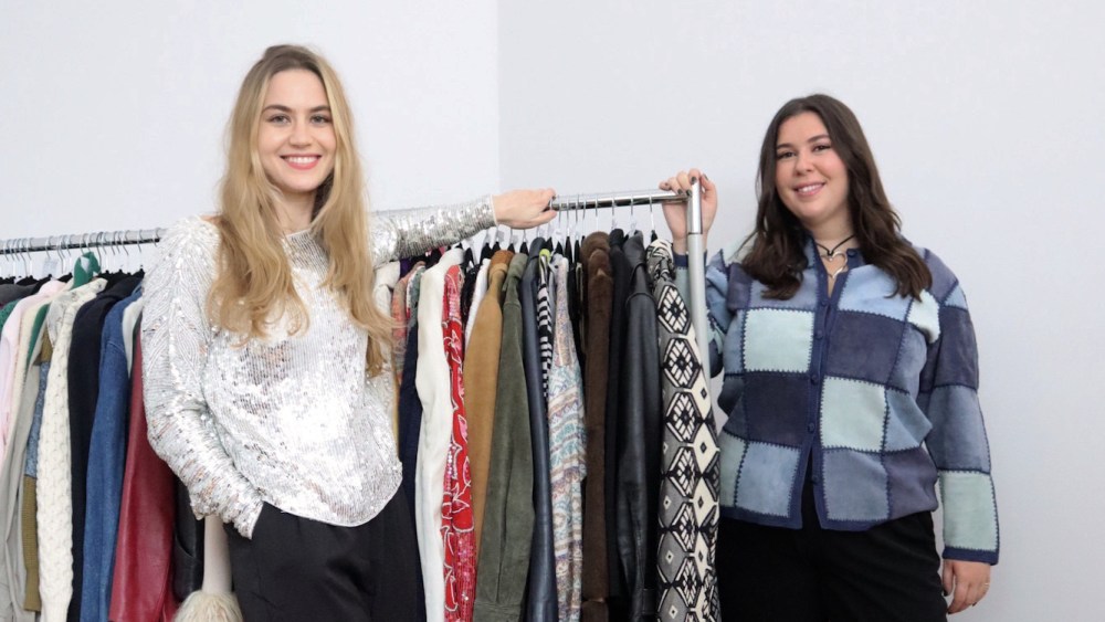 Hannah Levy and Abby Price, cofounders of South of Houston vintage marketplace stand with a rolling garment rack between them.
