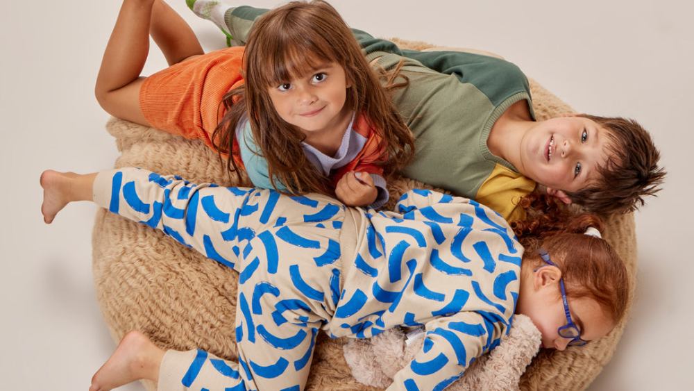 Three kids tangled up on a beanbag wearing Young Days sets.