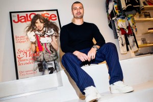 Sky Gellatly sits on a step in front of a large print of a magazine cover
