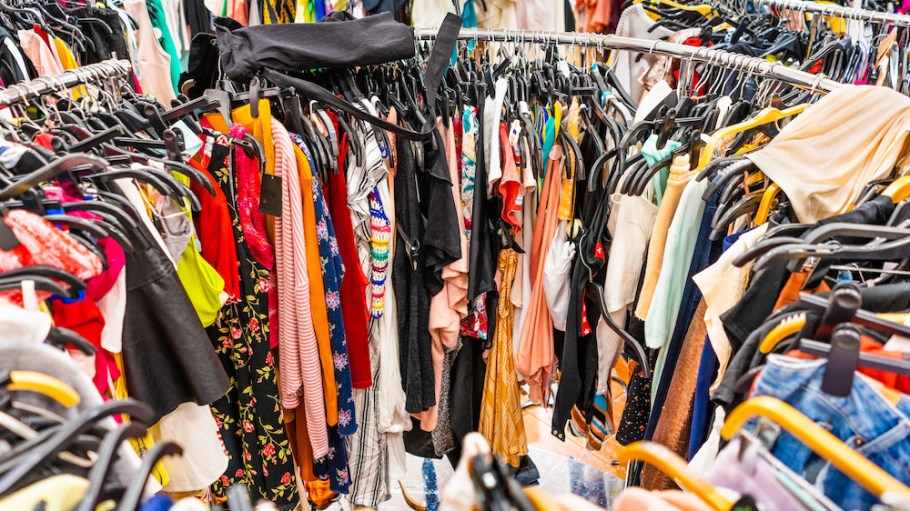 Crowded clearance section in a clothing store, with various colorful garments placed tightly on racks in no particular order; fast fashion concept